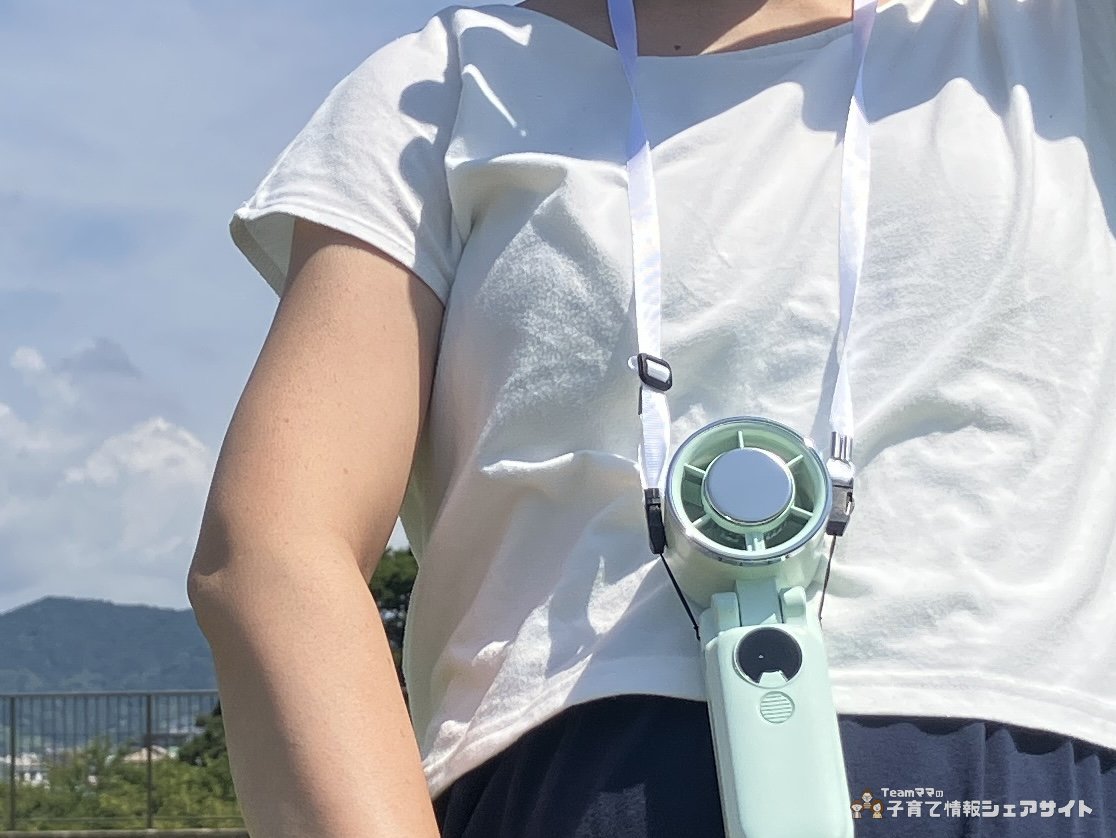大人が冷却プレートつきハンディファンを首から下げている様子 白いTシャツにミントグリーンの本体